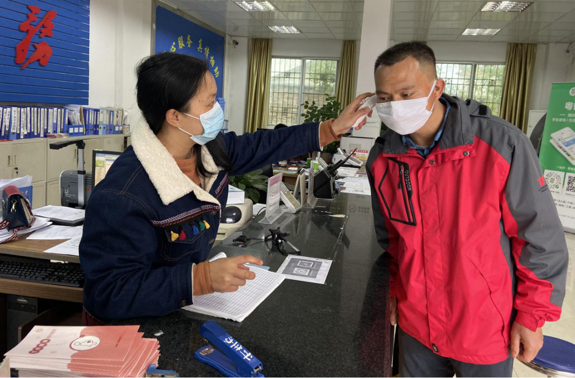 镇政府办事大厅工作人员为办事群众测量体温