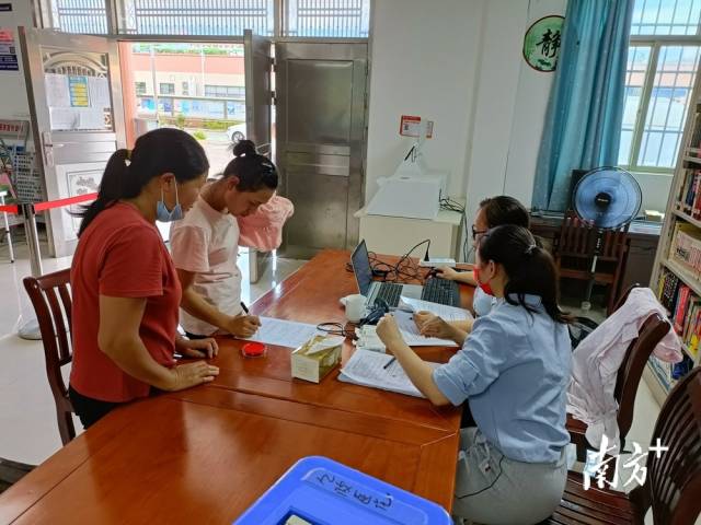 镇、村干部为村民进行接种信息录入。