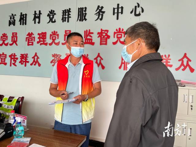 正在为群众办事的沈家江（左）。