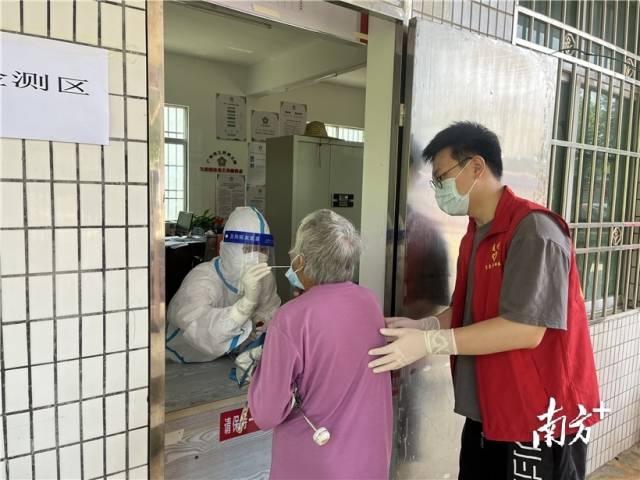 现场志愿者帮助行动不便群众接受核酸检测。