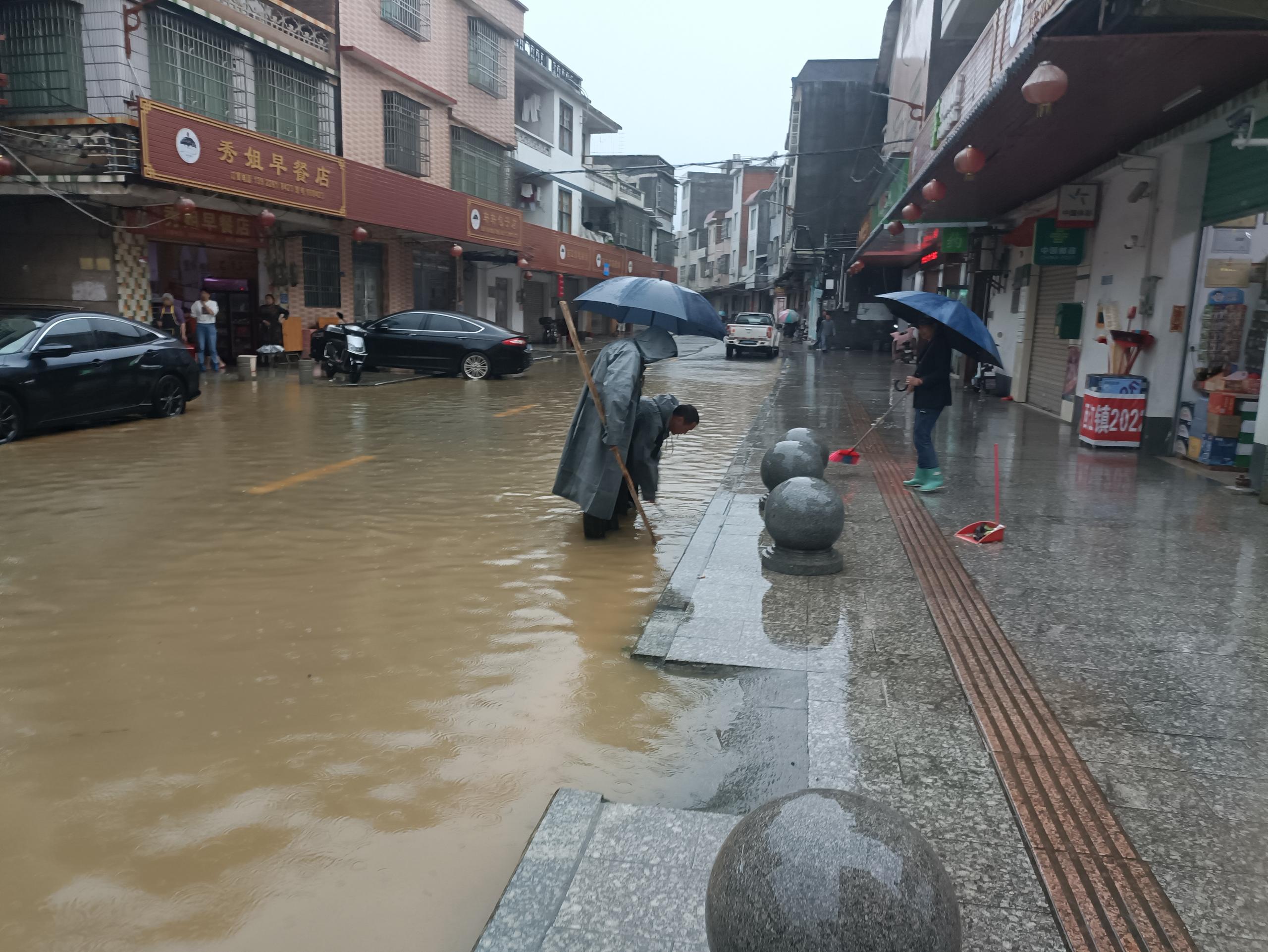 应急队伍在镇区积水路段疏通下水道.jpg